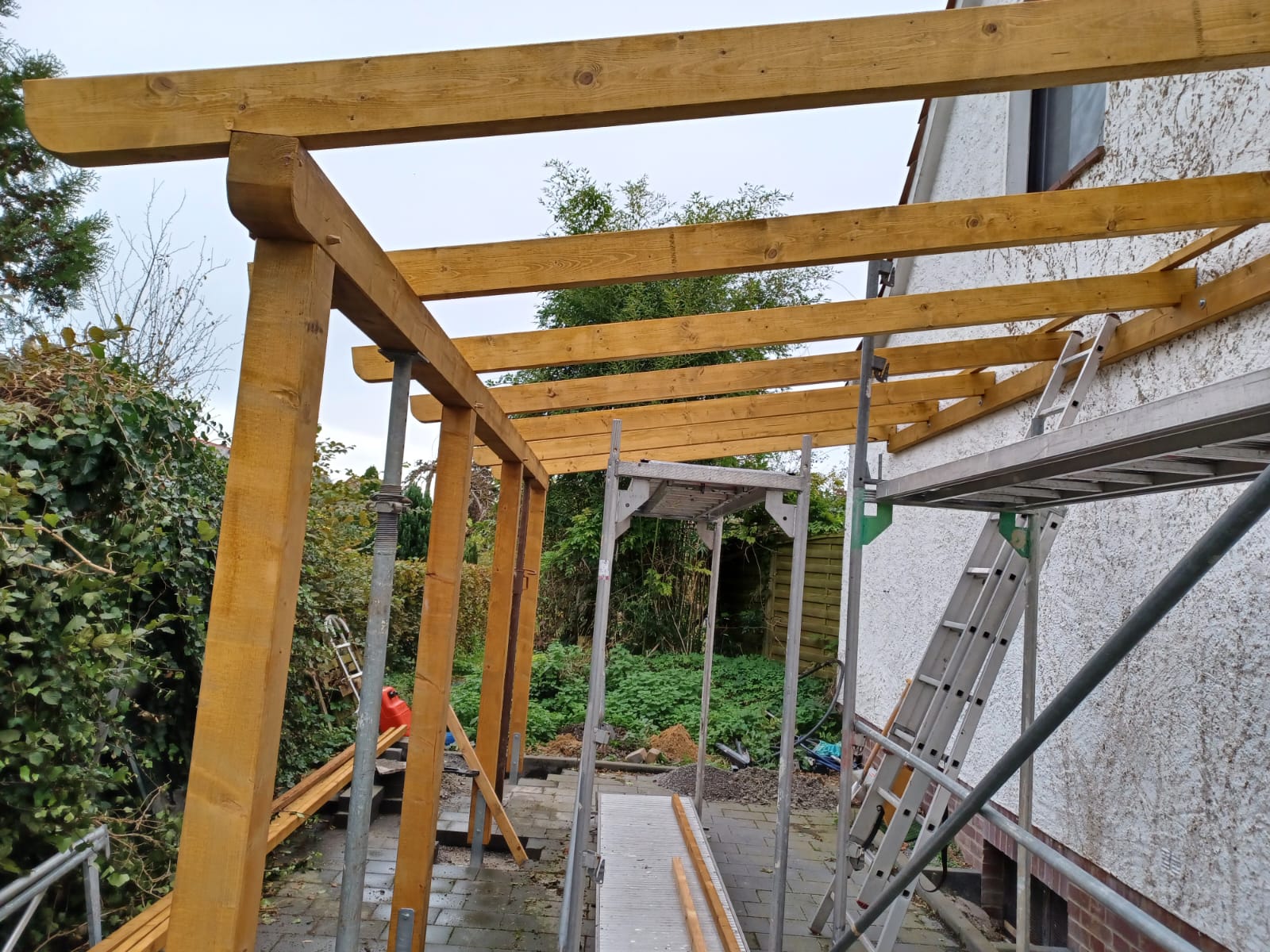 Neu errichtete Holzbalken einer Terrassenüberdachung während des Aufbaus